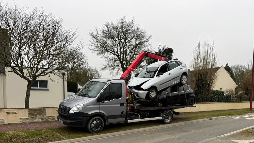 Deux voitures hors d'usage chargées sur le camion-grue, dans une rue
