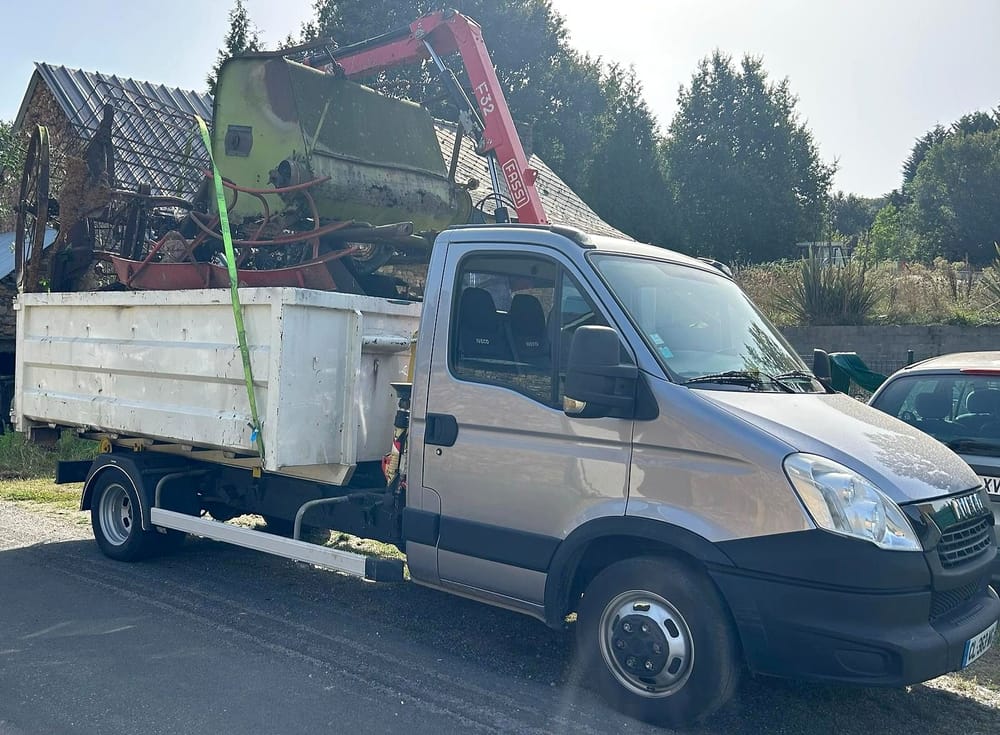 Chargement à la grue d'une machine agricole hors d'usage sur une benne pleine de ferraille